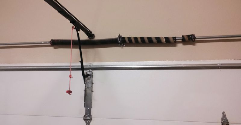 Broken torsion spring above a 16 by 7 double steel garage door